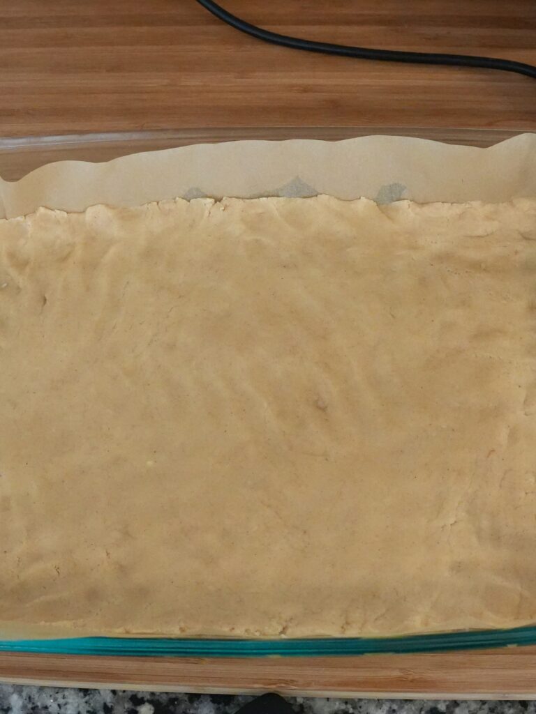 Press the dough evenly across the bottom of your prepared 9 × 13 baking dish
